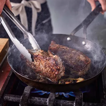 New York Strip Steaks being seared in a skillet