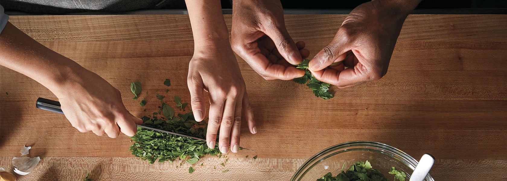 two chefs chopping herbs in kitchen