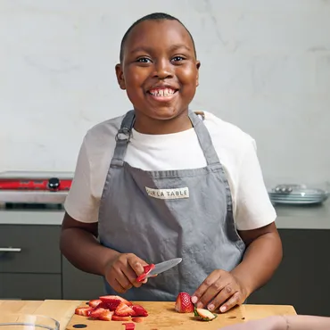 boy chopping strawberries in Sur La Table kitchen